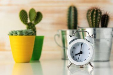Tahta masadaki kaktüslü beyaz çalar saat. Asgari zaman kavramı.