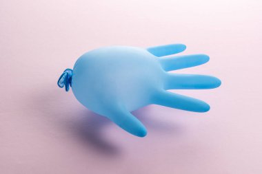 Pastel pembe arka planda mavi lateks tıbbi eldiven. Asgari Coronavirus salgını. Panik konsepti.