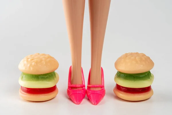 Colorful candy hamburger with a legs of doll. Minimal fitness food concept.