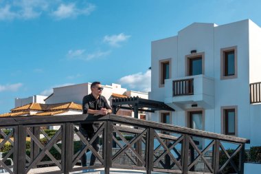 Otelde dikilen ve deniz kenarına bakan bir adam..