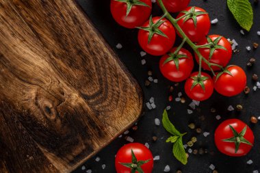 Siyah arka planda baharatlı taze kiraz domatesleri. Yemek arkaplanı. Üst görünüm.