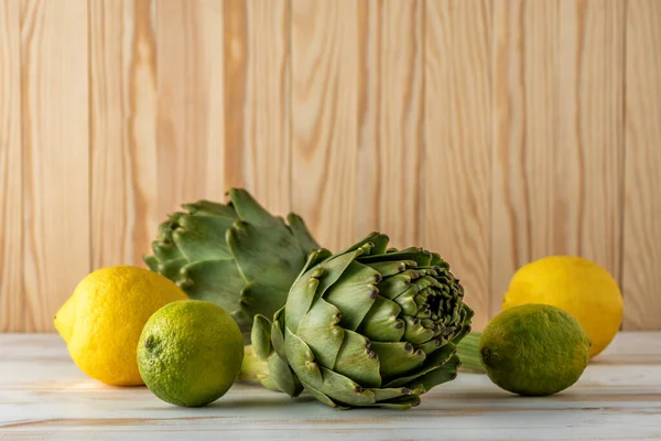 Mogna Ekologiska Kronärtskockor Ett Vitt Träbord Med Citron Vegetabilisk Bakgrund — Stockfoto