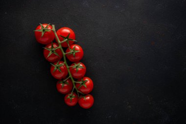 Siyah arka planda taze vişneli domates. Yemek arkaplanı. Üst görünüm.