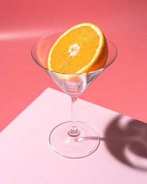 Parlak arkaplanda martini bardağında portakal meyvesi. Asgari içki konsepti.