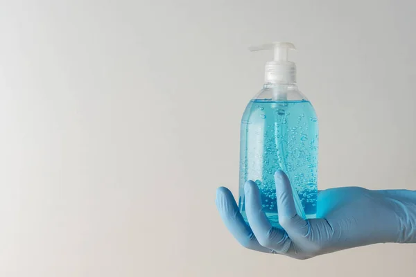 Beyaz arka planda bir şişede el dezenfektanı bulunan tıbbi eldiveni getirin. Coronavirus önleme kavramı.