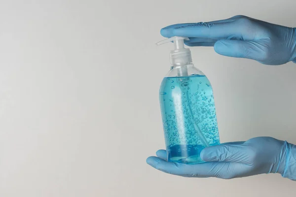 Hands in medical gloves with hand sanitizer in a bottle on white background. Coronavirus prevention concept.