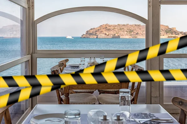 Barrier tape - quarantine, isolation concept, entry ban. Do not cross. View of Spinalonga Island from tavern.