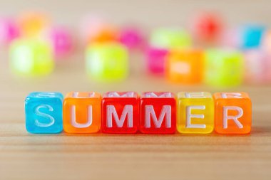 Tahta arka planda renkli harf küpleri olan YAZ metni. Asgari tatil kavramı.