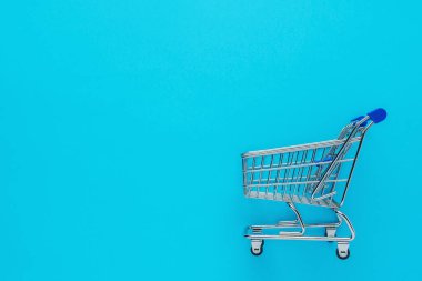 Mavi arka planda alışveriş arabası. Asgari Coronavirus salgını. Para biriktirme kavramı.