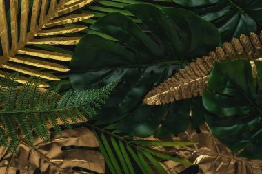 Siyah arka planda altın ve yeşil tropikal palmiye yaprakları olan yaratıcı bir düzen. Minimum yaz soyut şablonu.