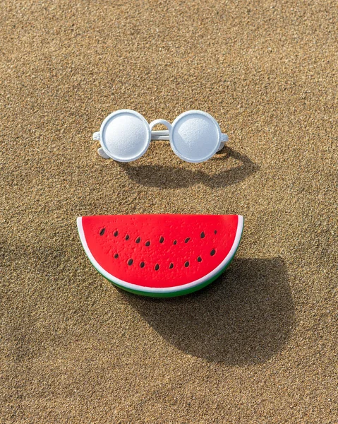 砂の背景にサングラスをかけたスイカのおもちゃ 最小限の夏休みのコンセプト — ストック写真