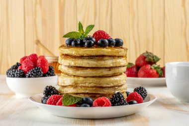 Beyaz ahşap masada taze böğürtlenli leziz krepler. Yiyecek konsepti.