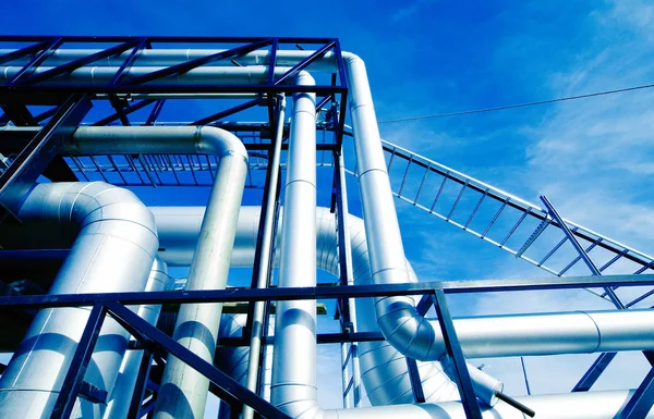 Zona industrial, dutos de aço e válvulas contra o céu azul — Fotografia de Stock