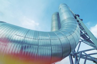 Mavi gökyüzüne karşı sanayi bölgesi, çelik boru hatları ve vanalar