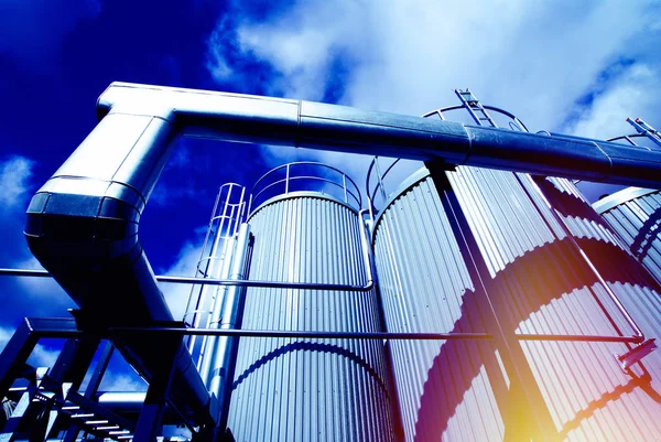 Zona industriale, tubazioni e valvole in acciaio contro il cielo blu — Foto Stock