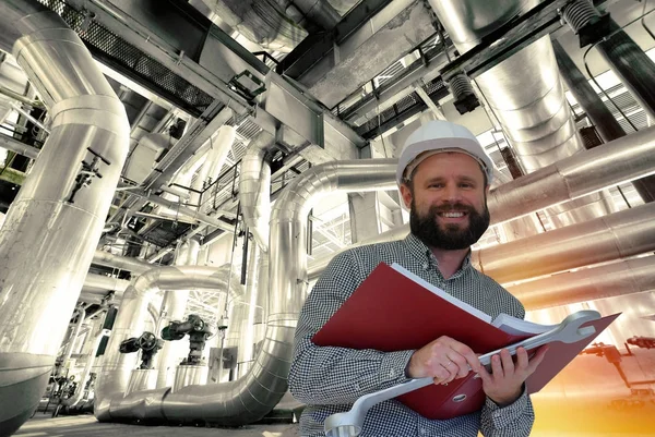 Engineer reading manual against factory equipment — Stock Photo, Image