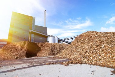 Mavi gökyüzüne karşı ahşap yakıt deposu olan biyo-elektrik santrali