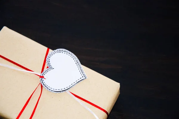 gift with label heart drawn on black wooden background