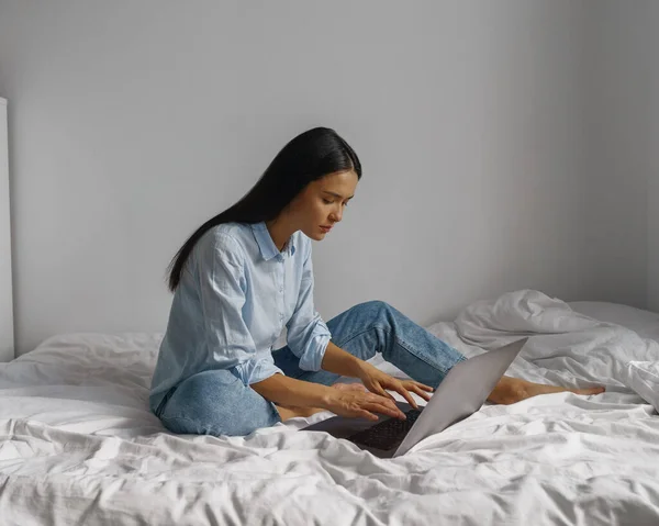ベッドのノートパソコンで自宅で働く若い女性 Lockdownart ストックフォト