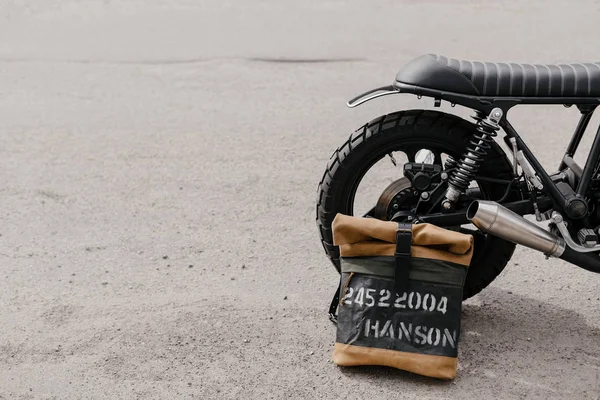 Mochila de cuero cerca de la motocicleta. Moto medio negro en el garaje. Motocicleta kaferacers . —  Fotos de Stock