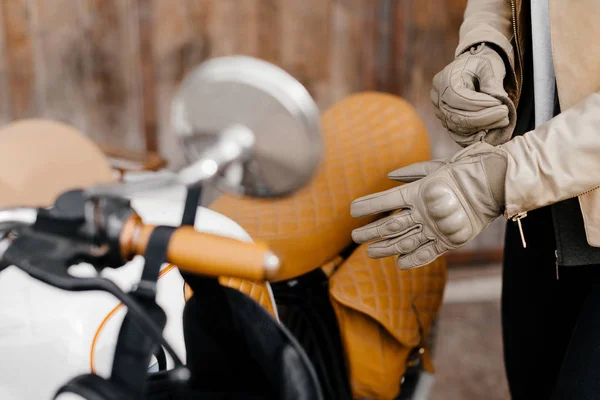 Kaferacers de motocicleta. Guantes de cuero de niña. Guantes de cuero beige. Guantes para andar en moto. Asiento de bicicleta marrón . Imagen De Stock