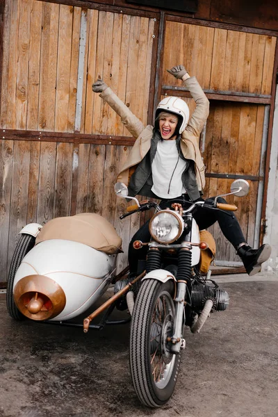Chica sonriente en una motocicleta. Chica feliz muestra emociones. Kaferacers de motocicleta. Motocicleta blanca con un gran sidecar. La chica grita felizmente —  Fotos de Stock