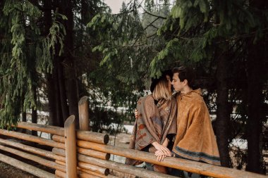 İki panço içinde. Adam bir panço, bir panço giymiş bir kadın giyinmiş. Seven çift ormanda
