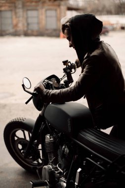 kadın onu bisiklet çeker. Garajda motosiklet. Bir kadında bir deri ceket. Motosiklet