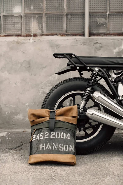 Mochila de cuero cerca de la motocicleta. Moto medio negro en el garaje. Mochila de cuero exclusiva. Mochila hecha a mano . —  Fotos de Stock