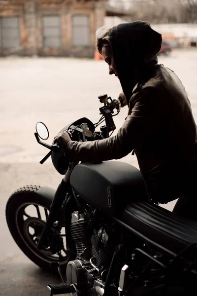 Mujer tira de su bicicleta. Motocicleta en el garaje. Una mujer con una chaqueta de cuero. Motocicleta Fotos De Stock Sin Royalties Gratis