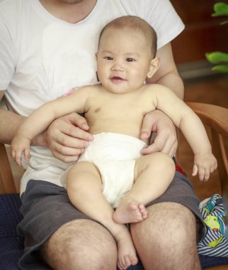 Bir bebek mutlu babasının kolundan gülüyordu