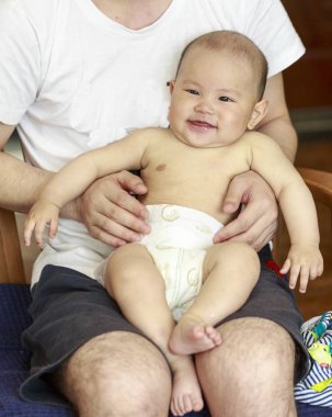 Bir bebek mutlu babasının kolundan gülüyordu