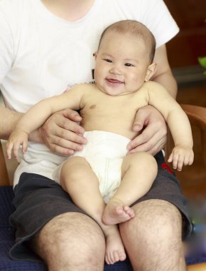 Bir bebek mutlu babasının kolundan gülüyordu