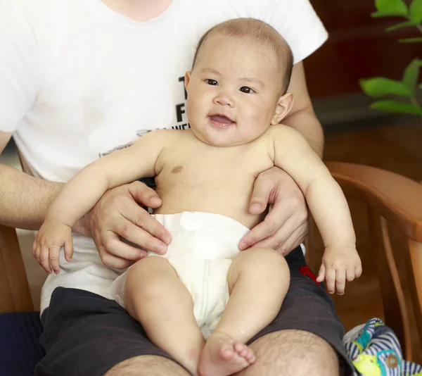 En baby lo lykkeligt i sin fars arm. - Stock-foto
