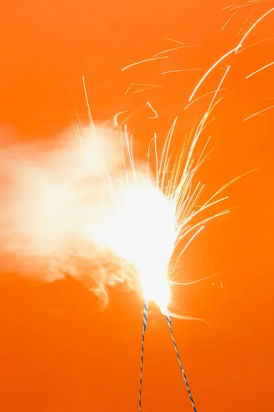 橙色背景下的两个燃烧烟花 — 图库照片