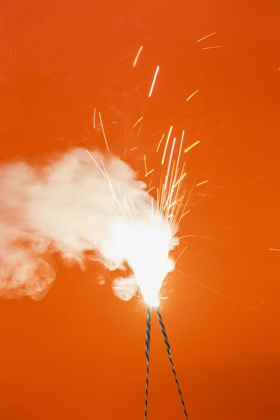 橙色背景下的两个燃烧烟花 — 图库照片