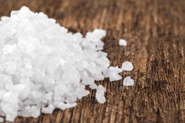 Bir avuç beyaz kristal deniz tuzu. Koyu ahşap bir masa üzerinde.