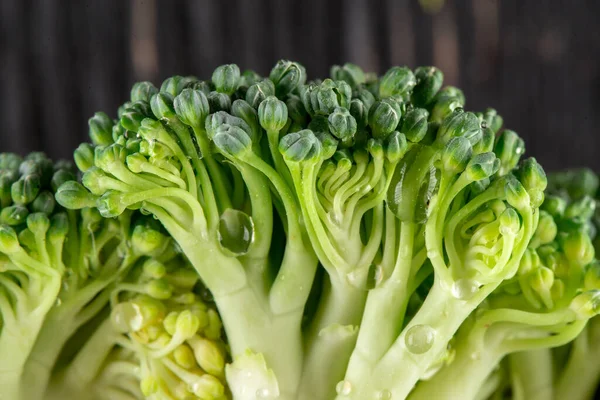 Macro view on ripe broccoli inflorescences on the dark wooden background — Stock Photo, Image