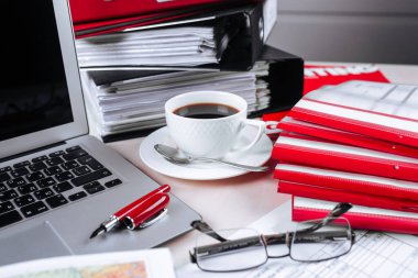 Ofis yeri dizüstü bilgisayarı kalem bardakları ve kahve rapor ediyor
