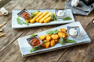 Kızarmış peynir çubukları ve soslu tavuk nuggetları.