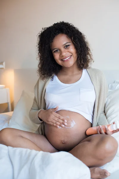 Femme enceinte hydratant ventre — Photo