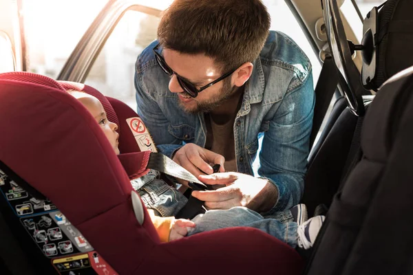 Babası onun bebek araba koltuğuna kemerlerinizi bağlayın — Stok fotoğraf