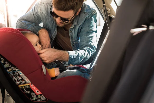 Pai prenda seu bebê no assento do carro — Fotografia de Stock