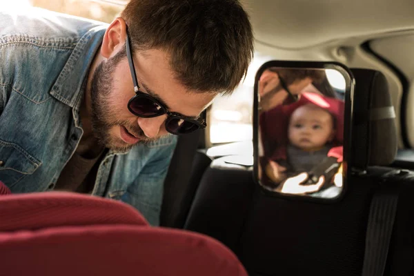 Ojciec zakończyć jego dziecko w foteliku samochodowym — Zdjęcie stockowe