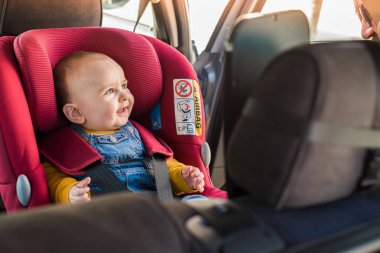 Father fasten his baby in car seat clipart