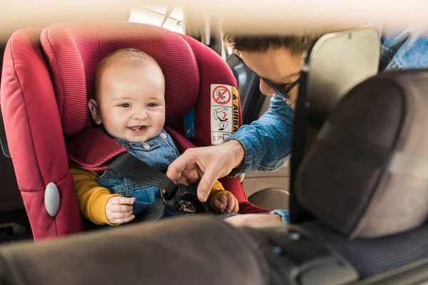 Pai prenda seu bebê no assento do carro — Fotografia de Stock