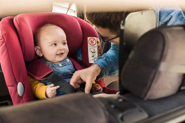 Padre sujetar a su bebé en el asiento del coche —  Fotos de Stock