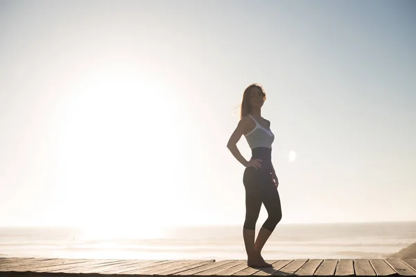 Donna in forma godendo il tramonto sulla spiaggia — Foto Stock