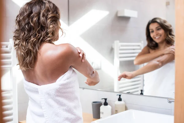 Mujer aplicando loción corporal — Foto de Stock