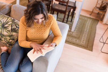 Kanepede kitap okuyan kadın.